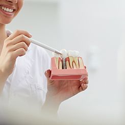 Dentist showing patient model of dental implant in Rockville, MD