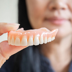 A woman holding a denture away from her mouth