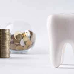 Tooth next to a bowl of coins