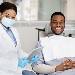 Dentist and patient smiling while reviewing information on tablet