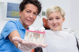 Dentist showing patient model of a dental implant