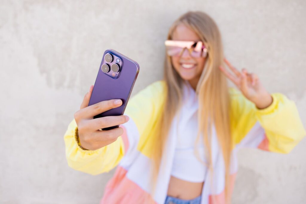 A teenage girl taking a selfie with her phone.